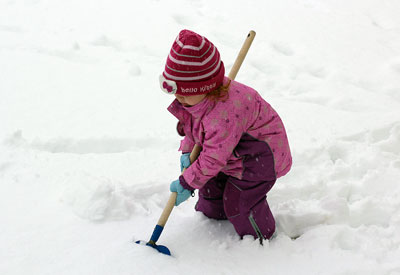 Ein Kind beim Schnee räumen